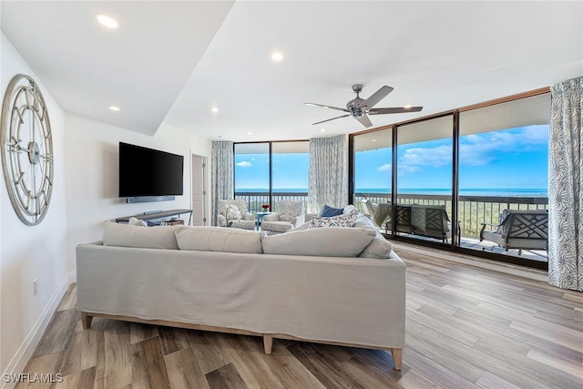 living area featuring ceiling fan, recessed lighting, wood finished floors, baseboards, and floor to ceiling windows