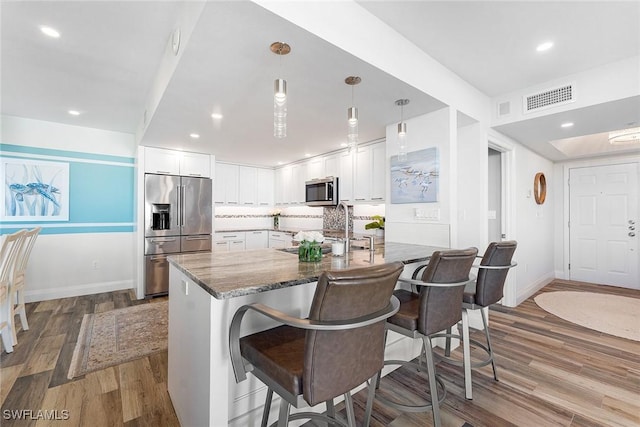 kitchen with a kitchen bar, visible vents, stainless steel appliances, and a sink