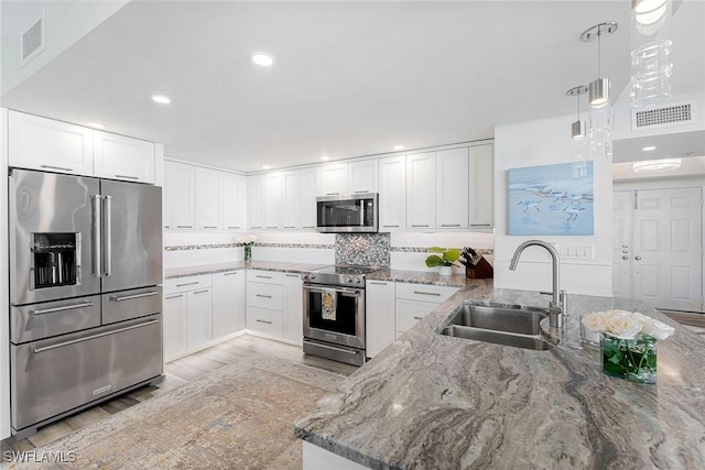 kitchen featuring appliances with stainless steel finishes, a sink, visible vents, and light stone countertops