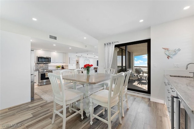 dining space with wine cooler, light wood-style flooring, recessed lighting, visible vents, and baseboards