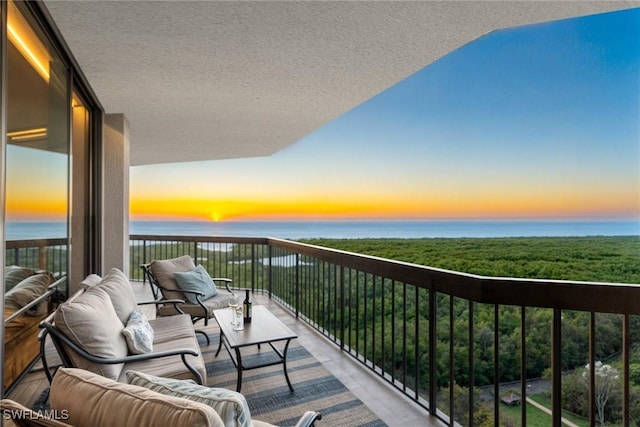 balcony at dusk featuring a water view