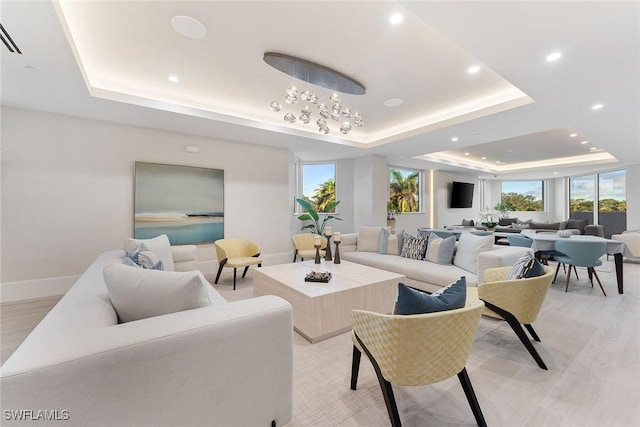 living room with light wood finished floors, a tray ceiling, and a wealth of natural light