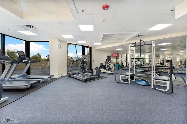 gym with expansive windows, visible vents, and a drop ceiling