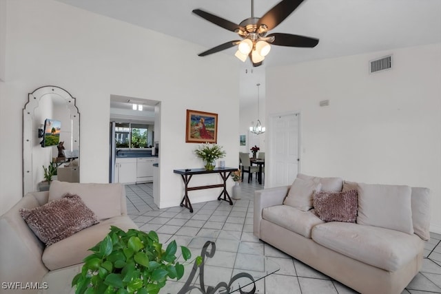 living room featuring high vaulted ceiling, light tile patterned floors, visible vents, and ceiling fan with notable chandelier