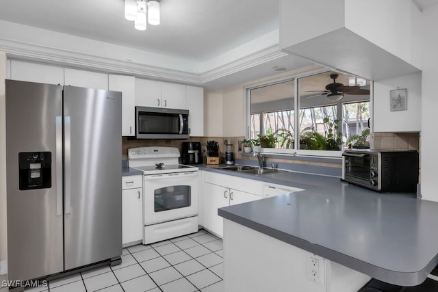 kitchen with dark countertops, white cabinetry, appliances with stainless steel finishes, and a sink