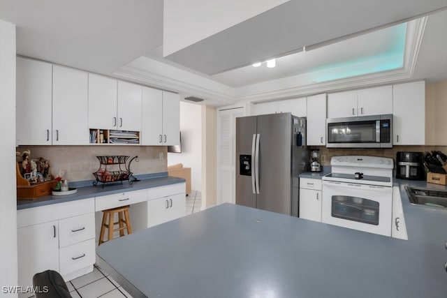 kitchen with white cabinets, stainless steel appliances, and a raised ceiling