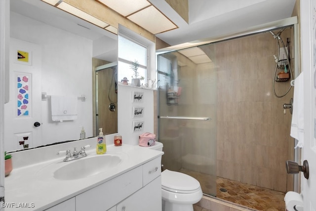 bathroom with toilet, a shower stall, and vanity