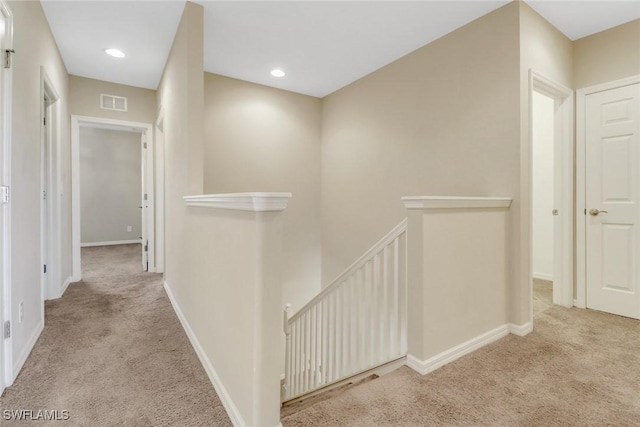 hall featuring an upstairs landing, visible vents, carpet floors, and baseboards