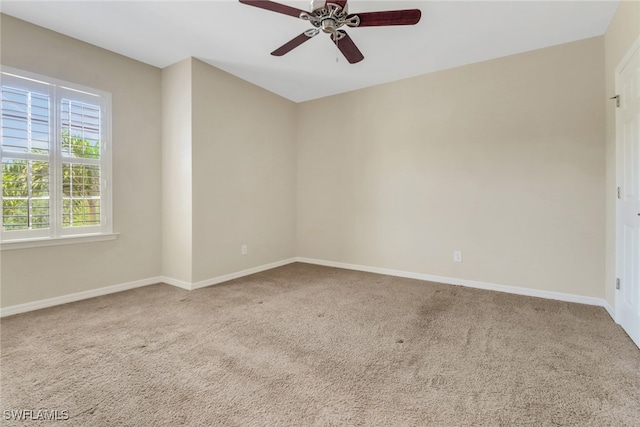 carpeted spare room with a ceiling fan and baseboards