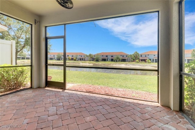 unfurnished sunroom featuring a residential view and a water view