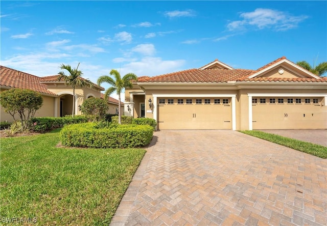 mediterranean / spanish-style house with a tiled roof, an attached garage, decorative driveway, a front lawn, and stucco siding