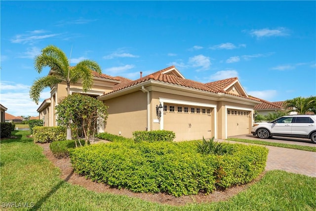 view of front of house featuring a garage, decorative driveway, a tiled roof, and stucco siding