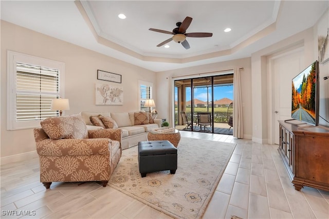 living area featuring crown molding, recessed lighting, a raised ceiling, a ceiling fan, and baseboards