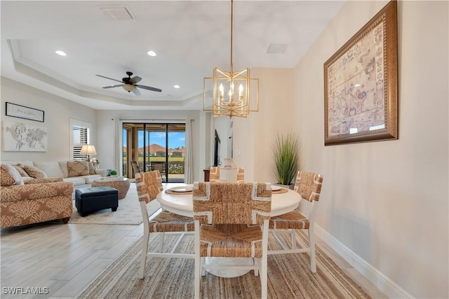 dining room featuring light wood-style flooring, a raised ceiling, visible vents, and baseboards