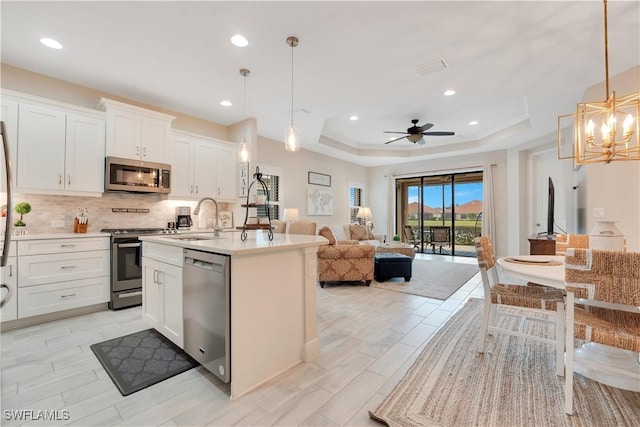 kitchen featuring stainless steel appliances, white cabinets, light countertops, and hanging light fixtures