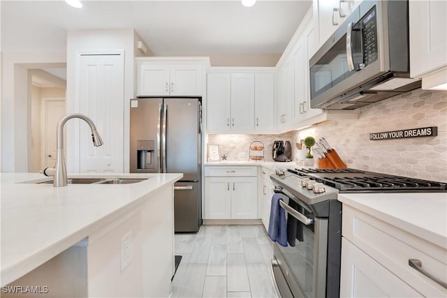 kitchen featuring appliances with stainless steel finishes, white cabinetry, a sink, and backsplash