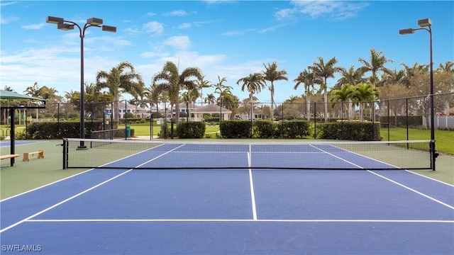 view of tennis court featuring community basketball court and fence