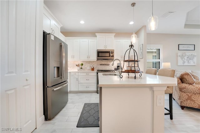 kitchen with stainless steel appliances, a breakfast bar, white cabinetry, light countertops, and decorative light fixtures