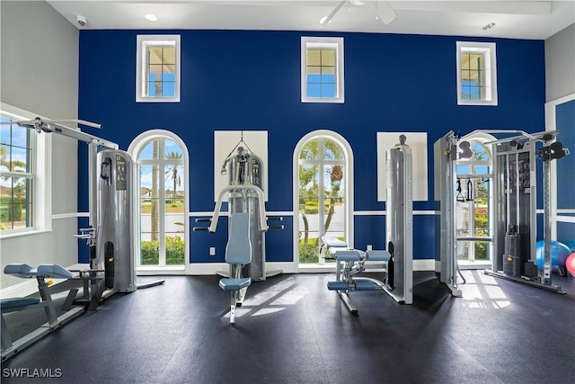 workout area featuring a towering ceiling, baseboards, and a ceiling fan