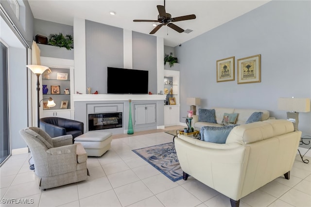 living room featuring light tile patterned floors, ceiling fan, and a glass covered fireplace