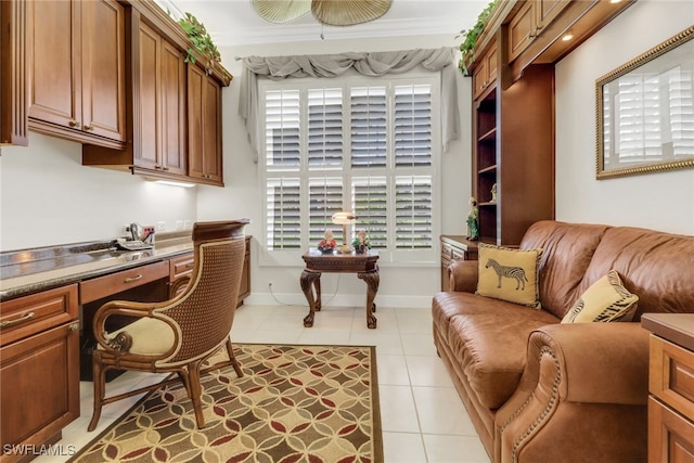 office area with light tile patterned floors, baseboards, ornamental molding, and built in study area