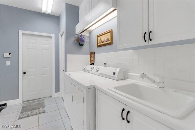 laundry room with light tile patterned floors, cabinet space, a sink, washer and dryer, and baseboards