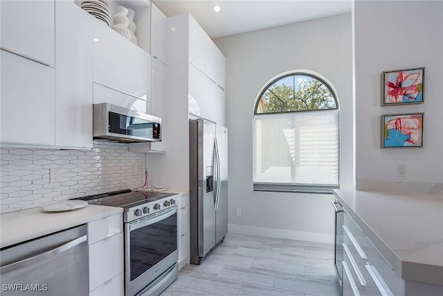 kitchen with white cabinets, modern cabinets, stainless steel appliances, and backsplash