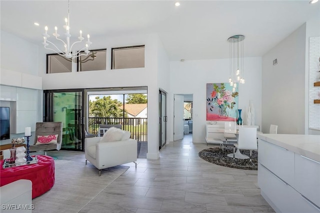 living area with a high ceiling, visible vents, and a notable chandelier