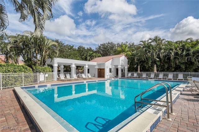 community pool with a patio area and fence