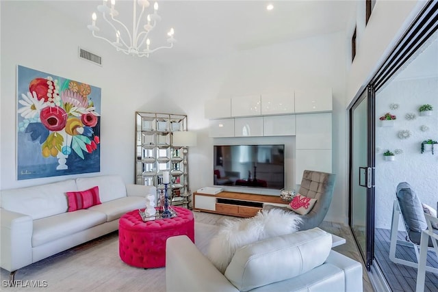 living area with wood finished floors, a towering ceiling, visible vents, and an inviting chandelier