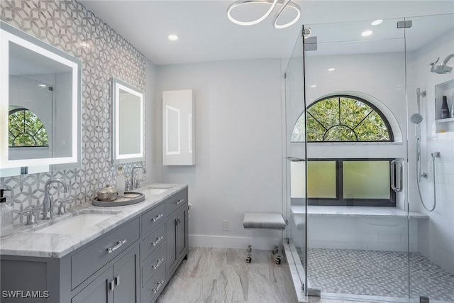 bathroom featuring a stall shower, a sink, and baseboards