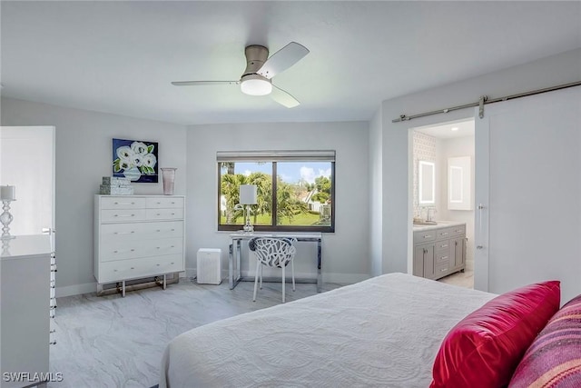 bedroom with a ceiling fan, connected bathroom, baseboards, and a barn door