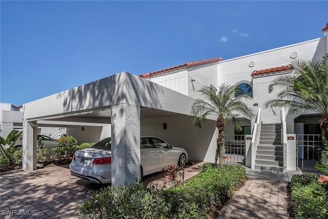 exterior space with a carport, stairway, and stucco siding