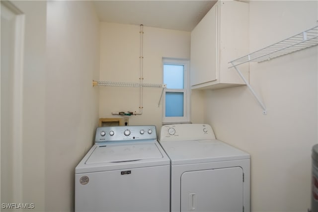 washroom featuring cabinet space and washer and clothes dryer