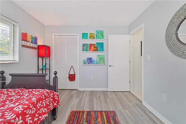 bedroom with light wood finished floors, baseboards, and a closet