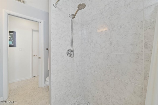 bathroom with a tile shower and toilet