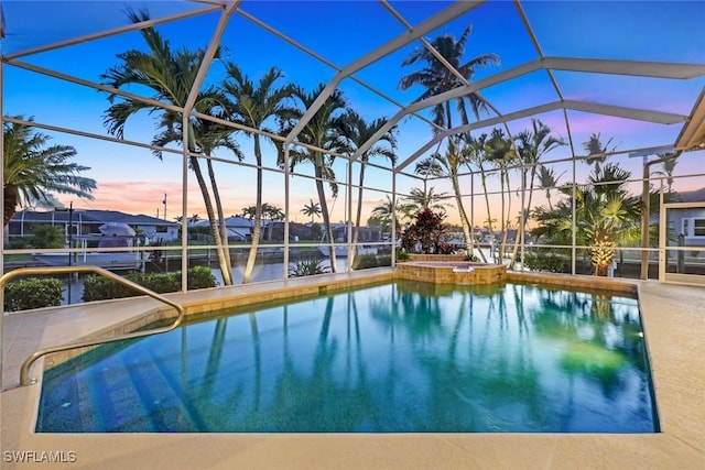 pool at dusk featuring a lanai, a water view, and a pool with connected hot tub