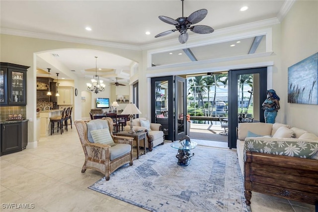 living area featuring ornamental molding, recessed lighting, arched walkways, and ceiling fan with notable chandelier