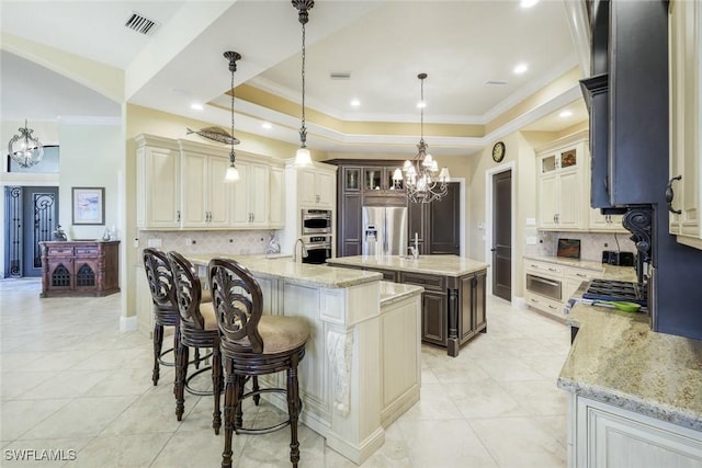 kitchen with hanging light fixtures, a large island, appliances with stainless steel finishes, a tray ceiling, and glass insert cabinets