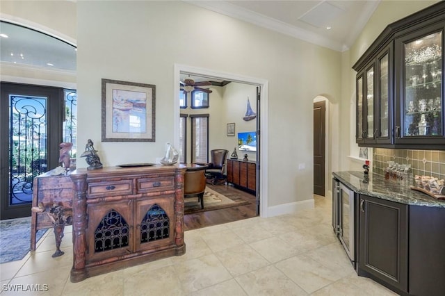 interior space with arched walkways, ornamental molding, wine cooler, and tasteful backsplash