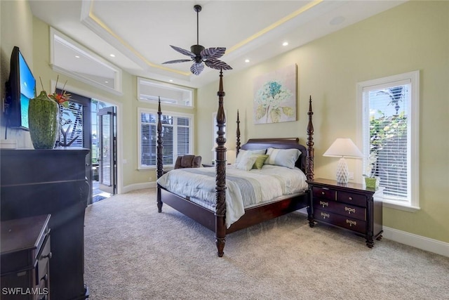 bedroom with light carpet, baseboards, access to exterior, a tray ceiling, and recessed lighting