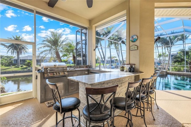 sunroom featuring a water view and a ceiling fan