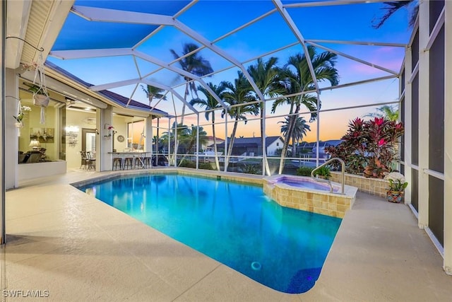 pool at dusk with a pool with connected hot tub, a lanai, and a patio