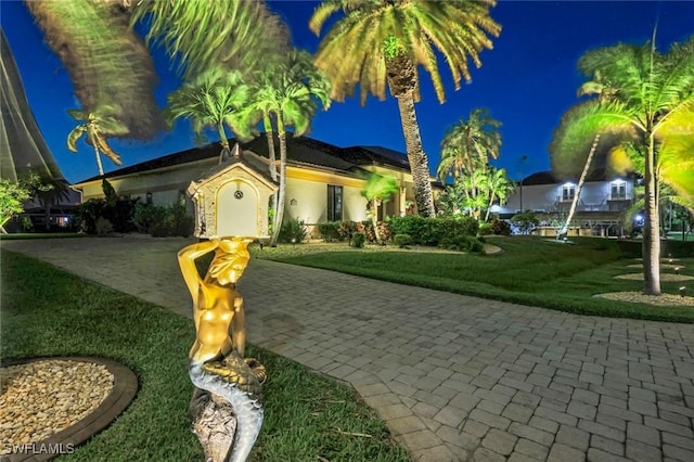 view of front of home featuring a lawn and decorative driveway