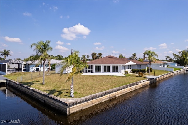 back of house with a yard, a water view, and fence