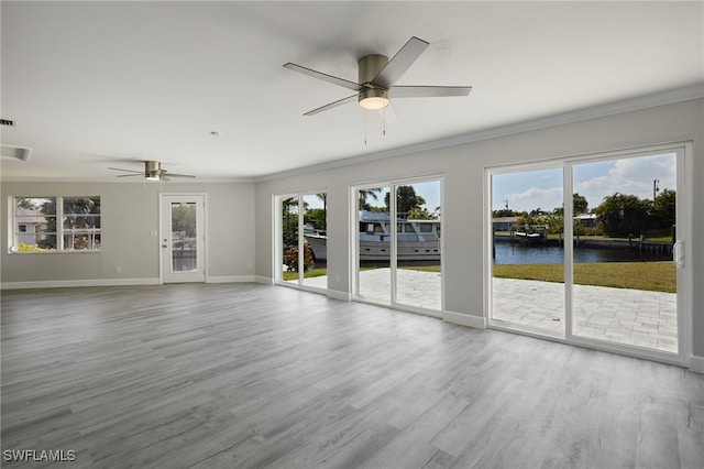 unfurnished living room with a wealth of natural light, crown molding, baseboards, and wood finished floors