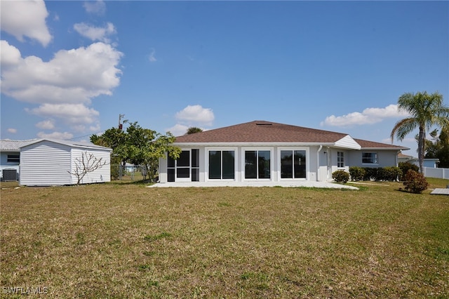 back of house with a yard, an outdoor structure, fence, and a sunroom