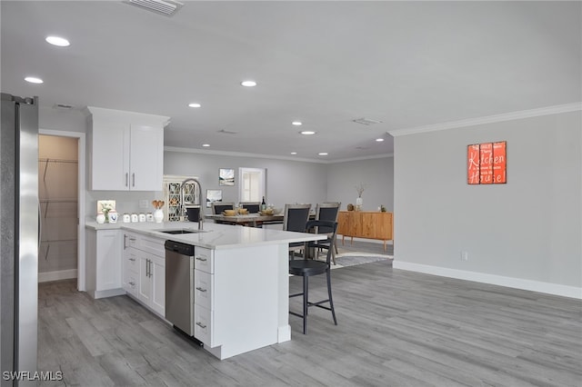 kitchen with a breakfast bar area, stainless steel appliances, a peninsula, a sink, and light countertops