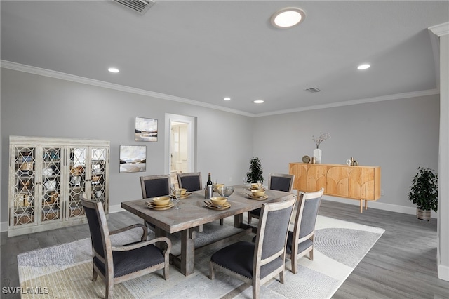 dining area featuring baseboards, visible vents, wood finished floors, and ornamental molding