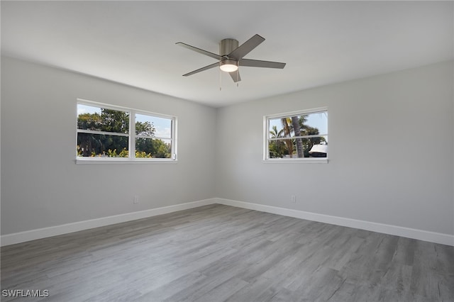 spare room featuring plenty of natural light, baseboards, and wood finished floors